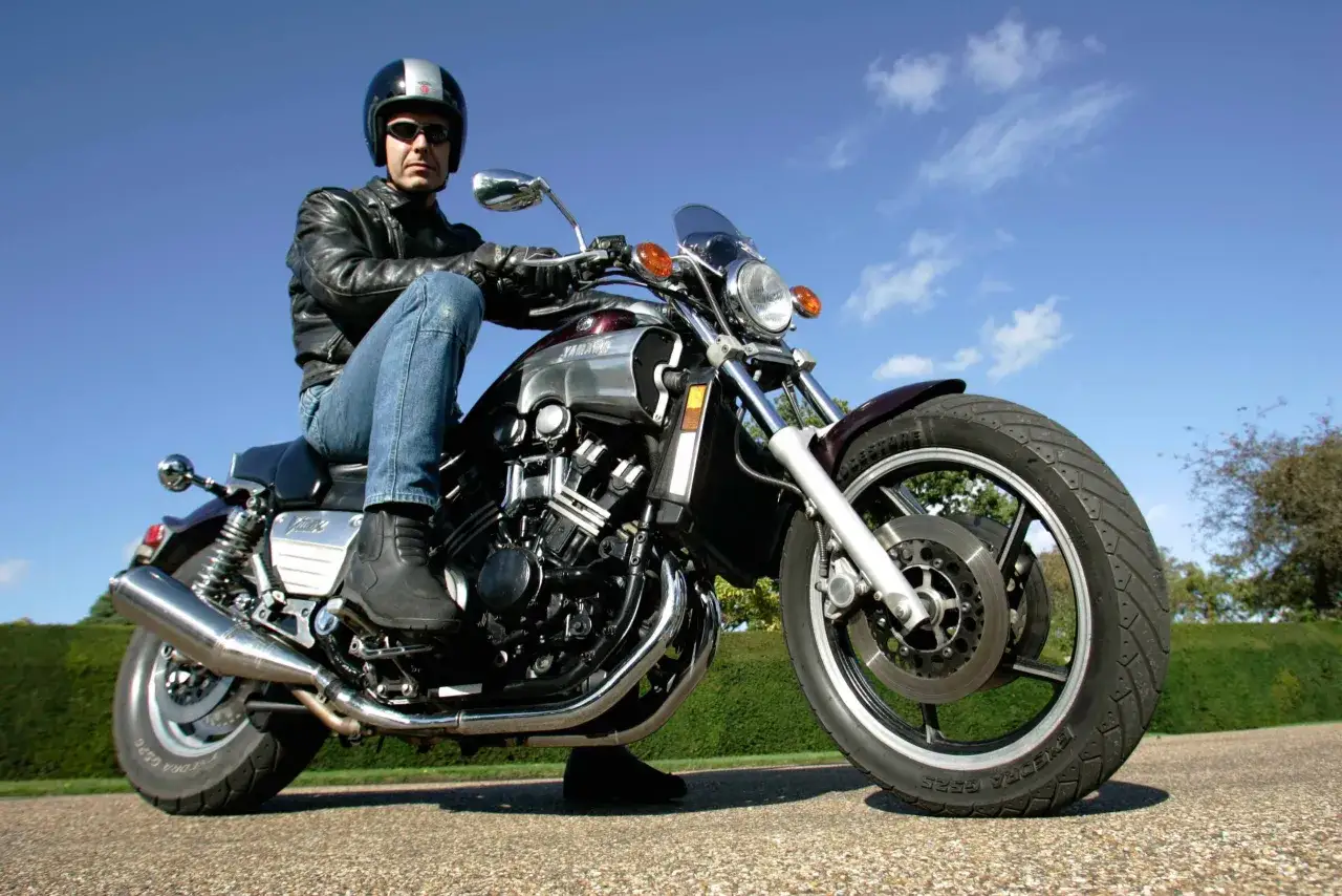 Mężczyzna w kasku i skórzanej kurtce siedzi na potężnym motocyklu Yamaha V-Max 1700.