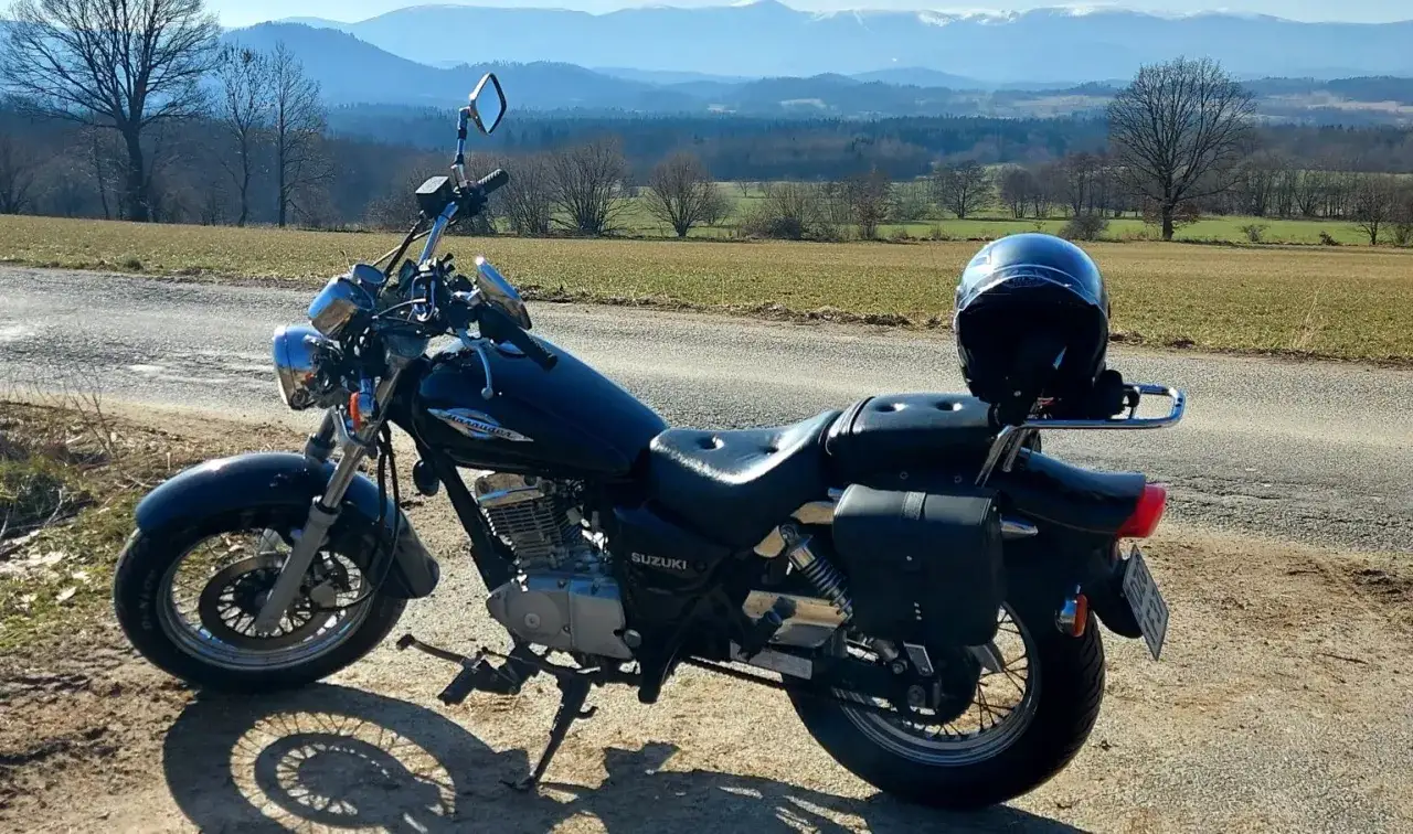 Czarny Suzuki Marauder na tle górskiego krajobrazu. Kask czeka na kierowcę, gotowego na przygodę.