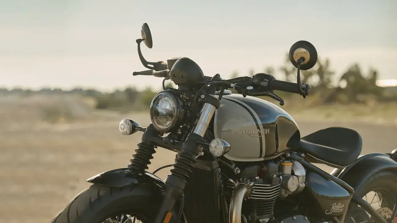 Stylowy motocykl Triumph Bobber z dwukolorowym malowaniem, gotowy na przygodę na pustynnej drodze.