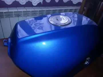 Błękitny, lśniący bak motocyklowy po malowaniu plastików. Widoczny metaliczny połysk i chromowany korek wlewu paliwa.