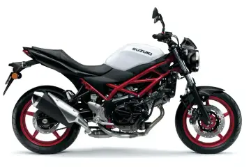Biały motocykl Suzuki SV 650S z czerwonym stelażem i felgami, gotowy do jazdy po mieście.
