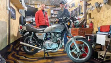Dwóch mężczyzn w garażu obok klasycznego motocykla Suzuki GS400.