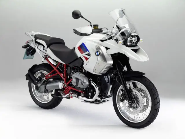 Biały motocykl BMW R1200GS z czerwonym stelażem i flagą na baku. Na co zwrócić uwagę: opony, felgi, silnik, siedzenie, owiewka.